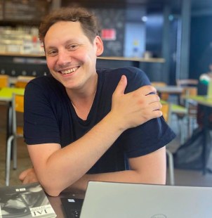 Élie Petit, fondateur de Marque Contente, souriant, assis devant son ordinateur